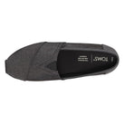 Top view of a single black Classic Canvas - Men alpargata by TOMS, with a rounded toe, diagonal stitching, classic slip-on design, and TOMS branding on the insole.