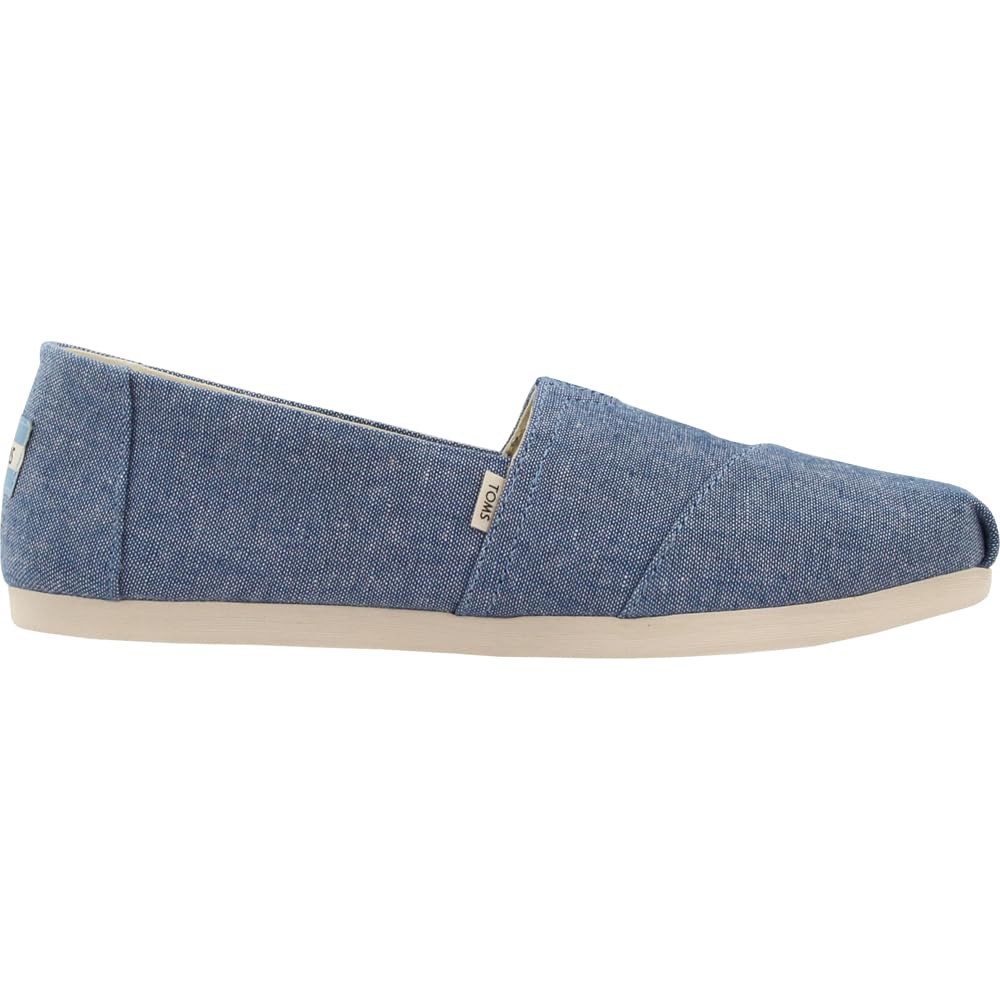 The TOMS Alpargata ESP - Women is a casual slip-on with light blue denim fabric, a beige rubber sole, a small branded tag by the opening, and supports TOMS buy one give one initiative. Shown in side view.