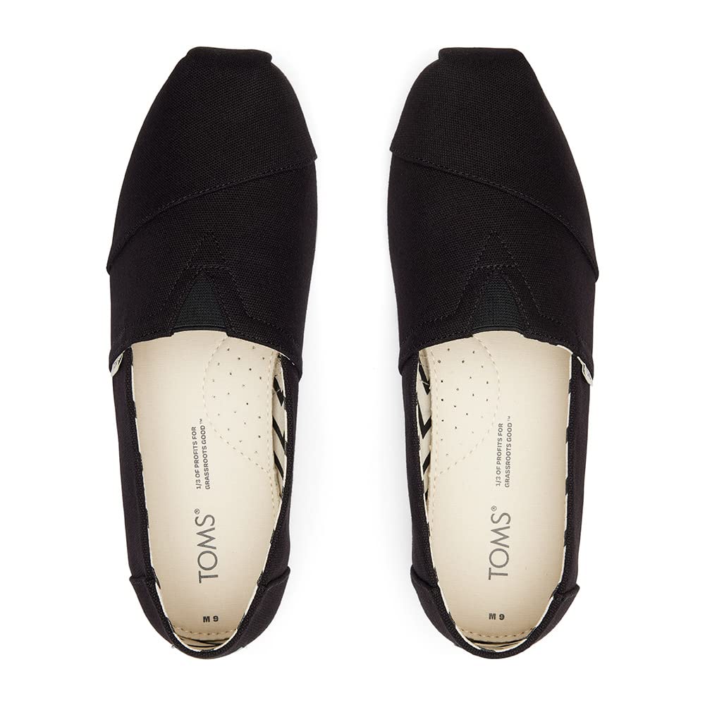 A pair of TOMS Classic Canvas - Men black slip-on shoes, viewed from above, with beige insoles featuring the TOMS logo and subtle perforations for breathability.