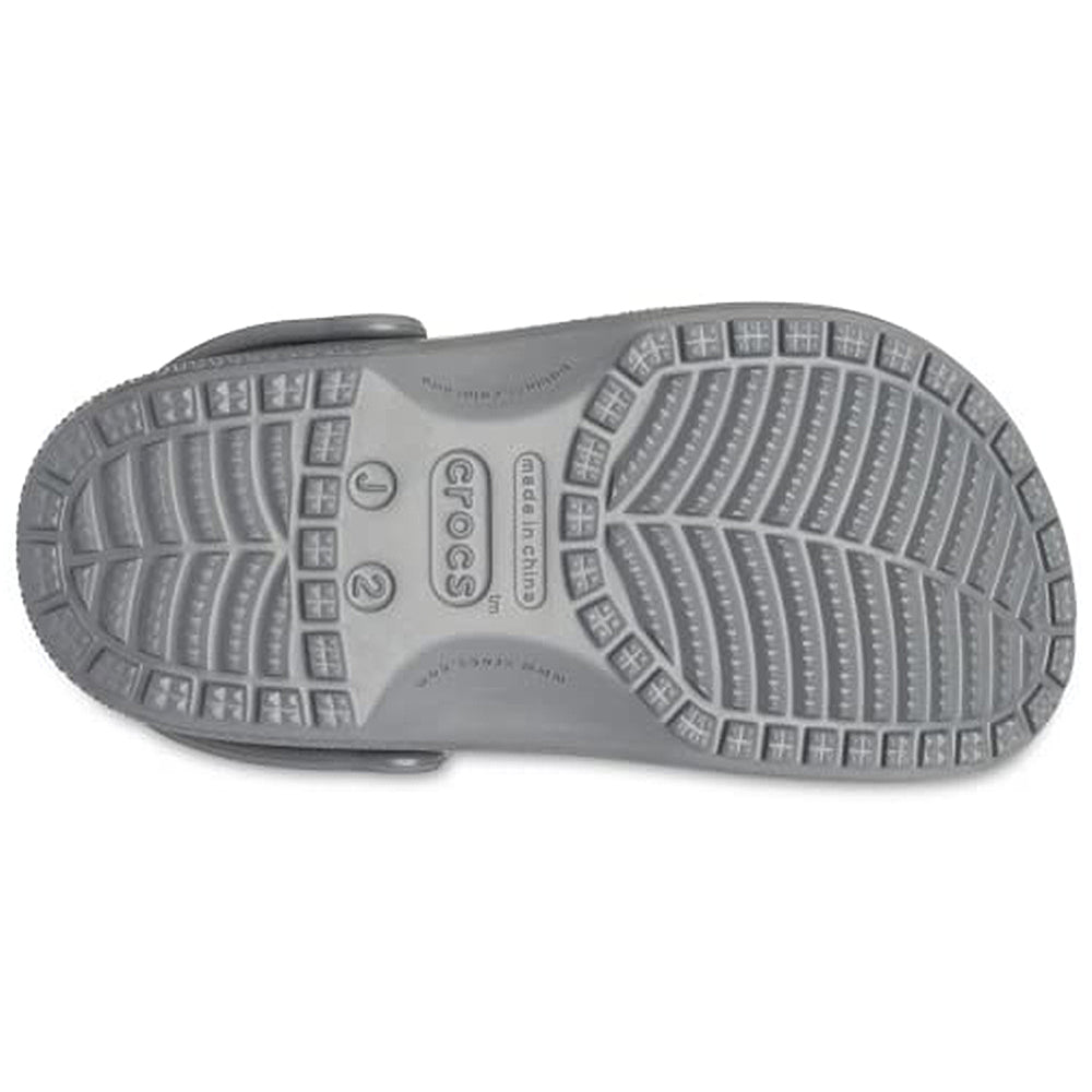 The underside of a single Crocs Classic Clog - Kids in gray shows the tread pattern with grip grooves, plus Crocs branding and size info at the center of the sole.