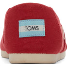Close-up of the back of a red TOMS Alpargata - Womens shoe featuring a light blue and white TOMS logo patch on the heel and a light-colored sole, made from recycled cotton.