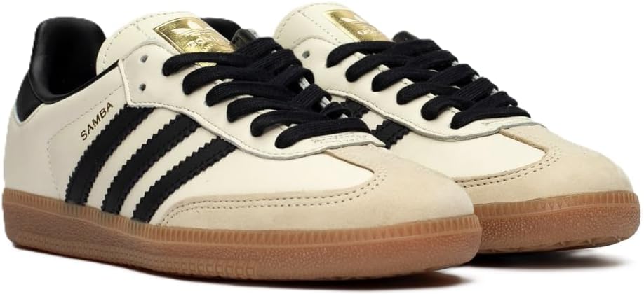 The adidas Samba OG - Women features Cream White leather uppers, Core Black stripes and accents, Sand Strata suede toe caps, black laces, brown gum soles, and a tongue with the gold adidas logo.