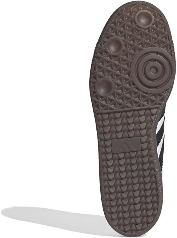 The image displays the black rubber sole of the adidas Samba OG - Men shoe, highlighting textured circular tread patterns. The iconic adidas logo appears at the center, combining street style with classic design.