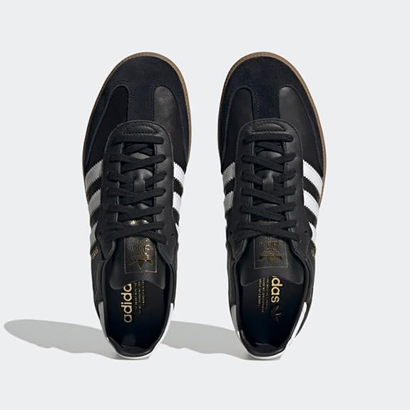 A pair of adidas Samba Decon Shoes for men with a black leather upper, white stripes, and gold logo details, shown from above on a light gray background.