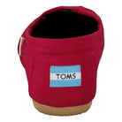 A rear view of the TOMS Alpargata ESP - Women in red, with the signature light blue and white TOMS logo on the heel, a tan sole, and representing their buy one give one philosophy.