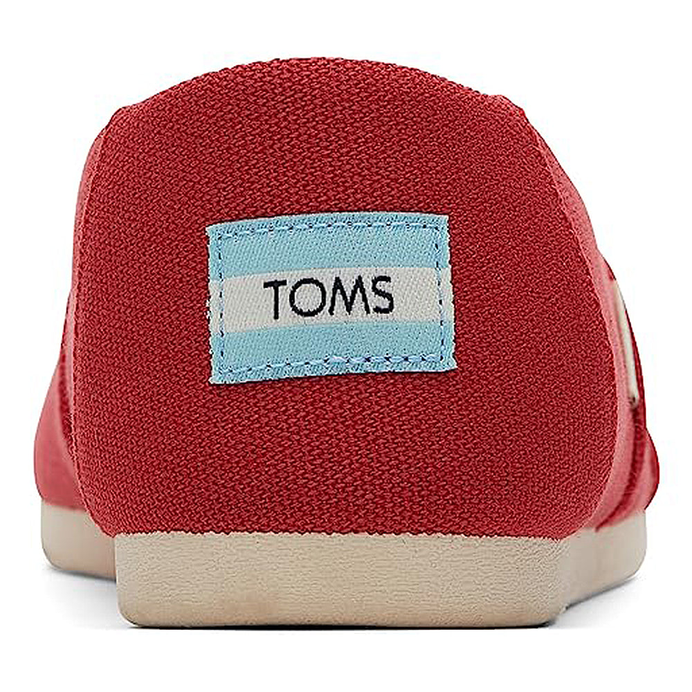 Close-up of the heel on a red TOMS Alpargata ESP - Women slip-on, with a light blue and white TOMS label and off-white rubber sole, highlighting the brands buy one give one mission.
