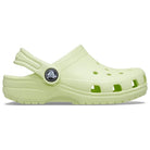 The Crocs Classic Clog - Kids is shown in light green with ventilation holes, a textured sole, and an adjustable heel strap in a side profile on a white background.