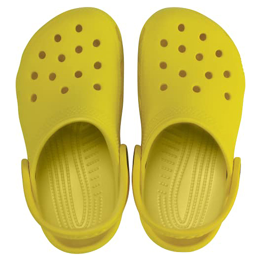 A pair of Crocs Classic Clog - Kids in bright yellow, featuring ventilation holes and adjustable heel straps, is shown from above on a white background.