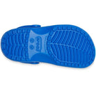 The image shows the blue sole of a Crocs Classic Clog - Kids, featuring its textured tread pattern, Crocs branding, and size details molded into the sole.