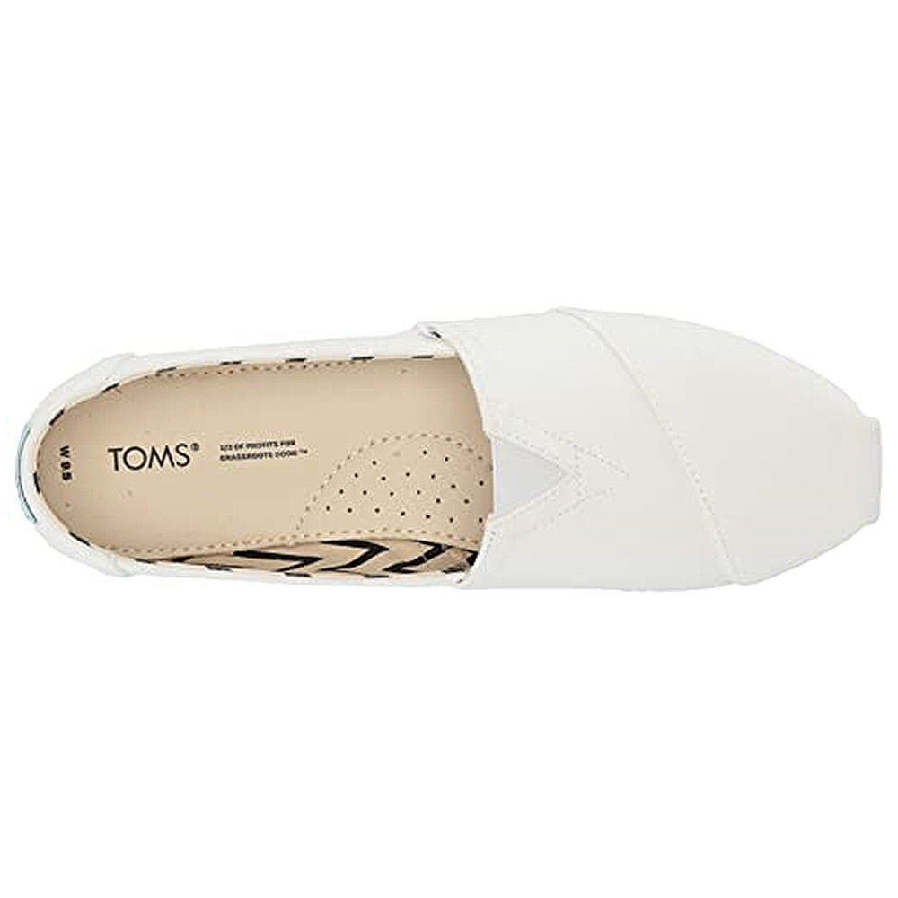 Top view of the Alpargata - Womens slip-on by TOMS, featuring a white upper, beige insole with black patterns and perforations for breathability. Part of the earthwise collection with recycled cotton; TOMS logo printed near the heel.