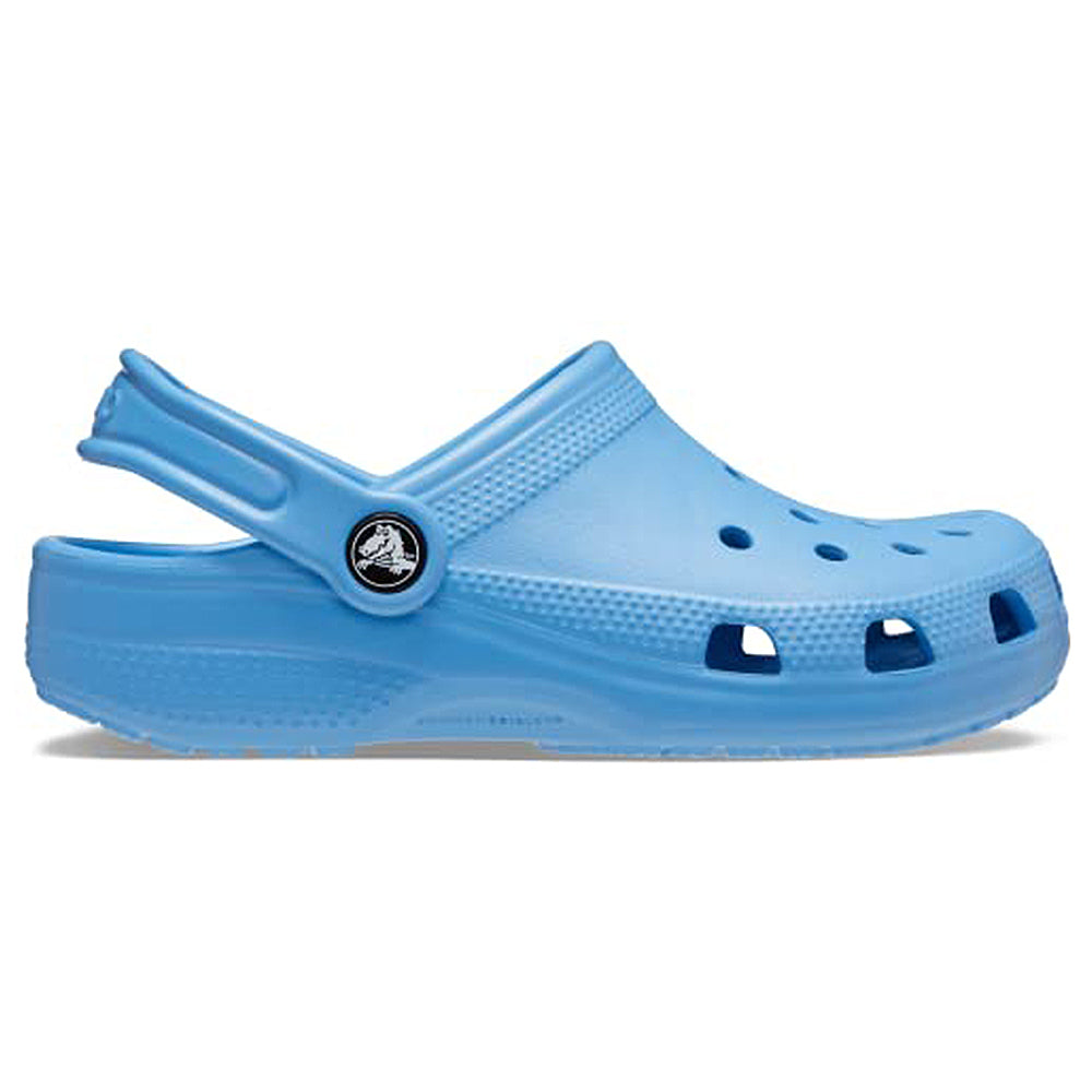 The Crocs Classic Clog - Kids is shown in light blue from the side on a white background, featuring ventilation holes, a textured sole, and an adjustable heel strap.
