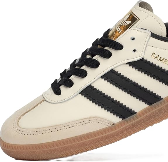The adidas Samba OG - Women features a cream leather upper, black stripes and laces, beige suede toe, gold adidas branding on the tongue, and a gum rubber sole—classic style reimagined for women.