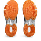 The image shows the orange and white rubber soles of ASICS Gel-Rocket 11 - Womens indoor court shoes. The sole’s circular, radiating tread pattern is engineered for enhanced grip, stability, and traction.