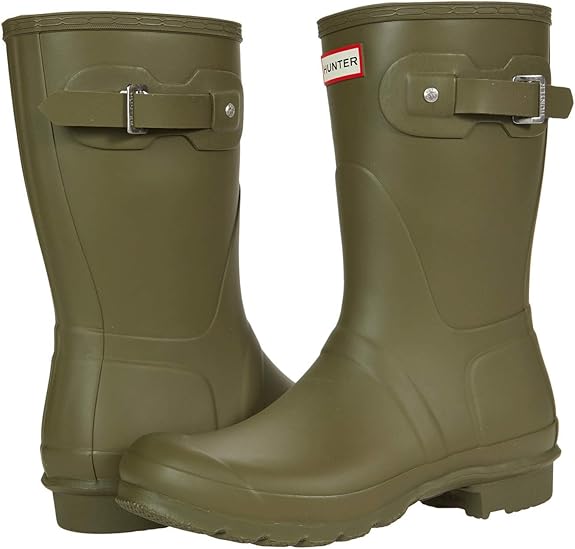 A pair of olive green Hunter Original Short Rain Boots for women, featuring adjustable side straps and textured soles—one boot upright, the other angled forward—for a stylish festival look.