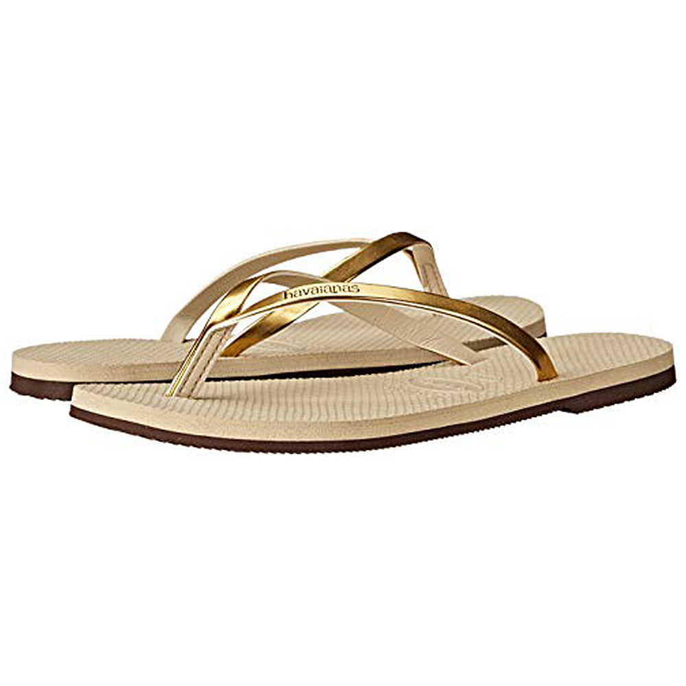 A pair of Havaianas Slim Metalic - Womens beige sandals with textured soles and metallic gold straps, shown against a white background.