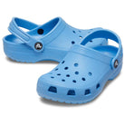 A pair of Crocs Classic Clog - Kids in light blue, featuring holes on top and adjustable heel straps, displayed on a white background.