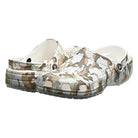 A pair of Crocs Classic Camo Clog - Unisex slip-on shoes in beige, brown, and white camouflage with ventilation holes and adjustable heel straps, displayed at a slight angle.