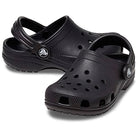 The Crocs Classic Clog - Kids in black features ventilation holes, an adjustable heel strap, and textured soles, shown against a white background.
