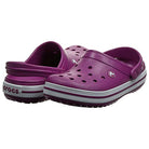 A pair of Crocs Crocband Clog Seasonal Colors - Unisex in purple, featuring ventilation holes and a white-striped sole, is shown with one upright and one tilted to display the heel strap and side details, available for purchase.