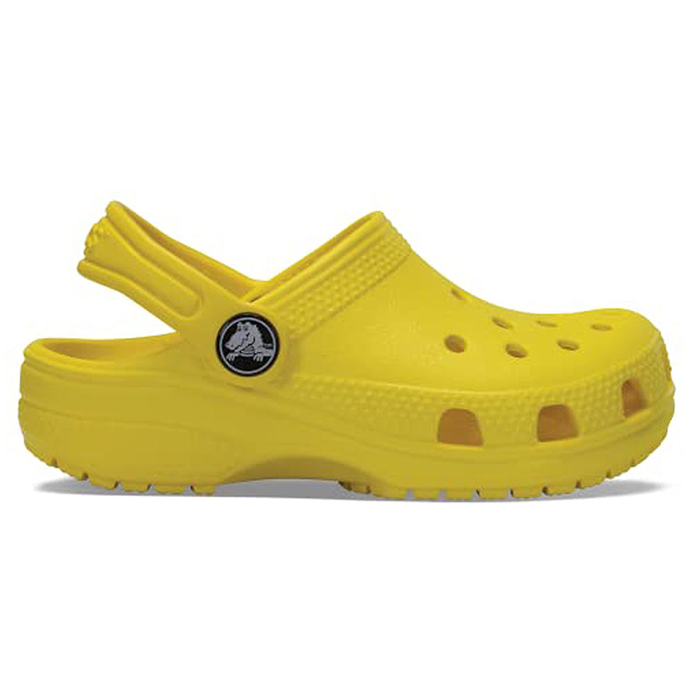 A side view of the Crocs Classic Clog - Kids in bright yellow, featuring ventilation holes and a pivoting heel strap, shown on a white background.