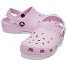 A pair of light pink Crocs Classic Clog - Kids with ventilation holes, adjustable heel straps, and textured soles is displayed on a white background.