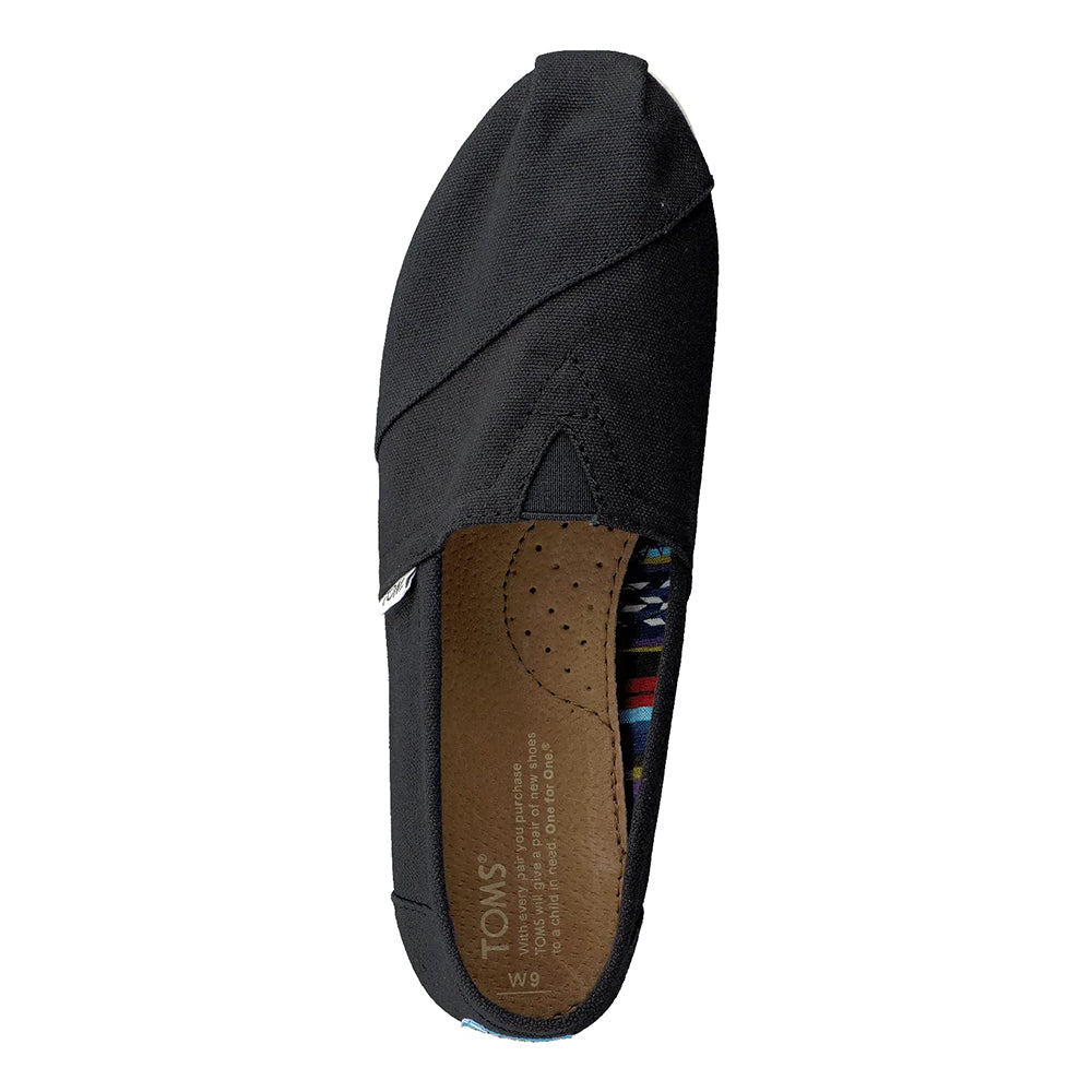 A top view of the TOMS Classic Canvas - Men slip-on in black, showcasing the signature alpargata design, a brown perforated insole, and subtle pattern accents by the heel.