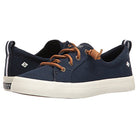 The Crest Vibe - Womens by Sperry is a navy blue canvas sneaker with white rubber soles, brown leather laces, and branding on the heel and side. It’s durable and provides comfortable arch support for all-day wear.