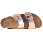 The Birkenstock Arizona - Womens sandal features two chunky metallic rose gold straps with adjustable buckles, a cork footbed for orthopedic comfort, and blue size markings on the insole.