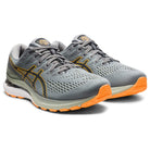 A pair of mens ASICS Gel Kayano 28 stability running shoes in gray with black details, orange soles, and the ASICS logo, featuring GEL technology and shown at an angle on a white background.