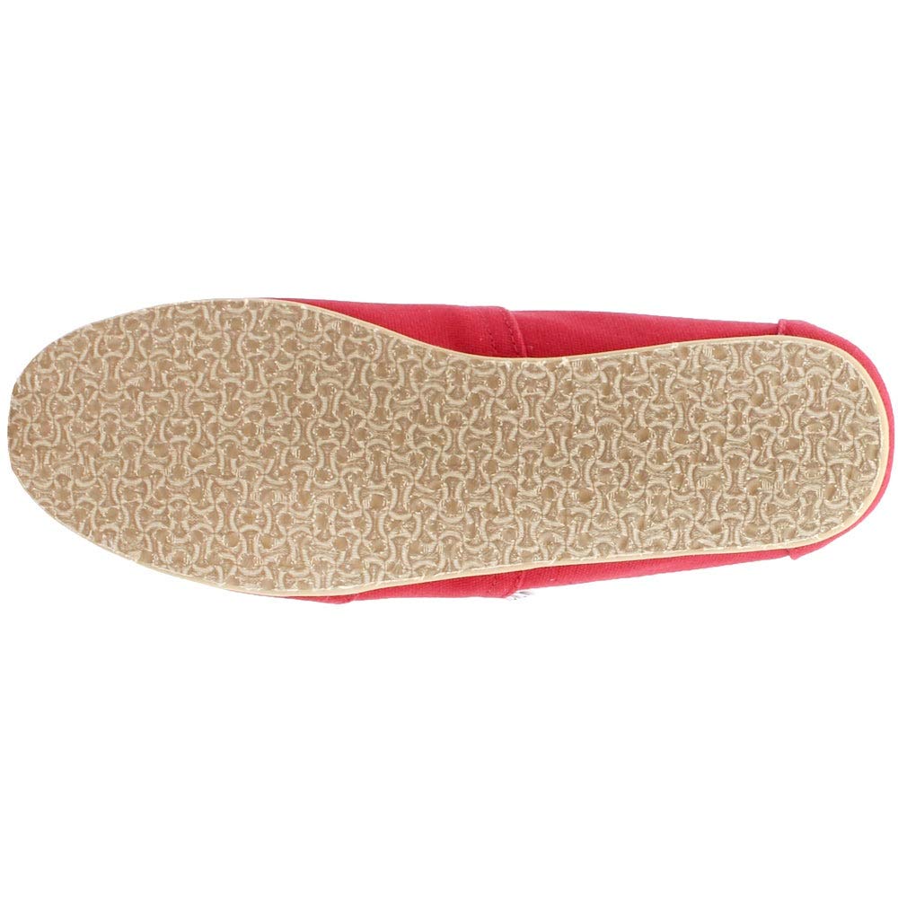 The image shows the bottom view of a TOMS Classic Canvas - Men slip-on in red, featuring a tan rubber sole with a wavy textured grip, characteristic of the brand’s classic alpargata style.