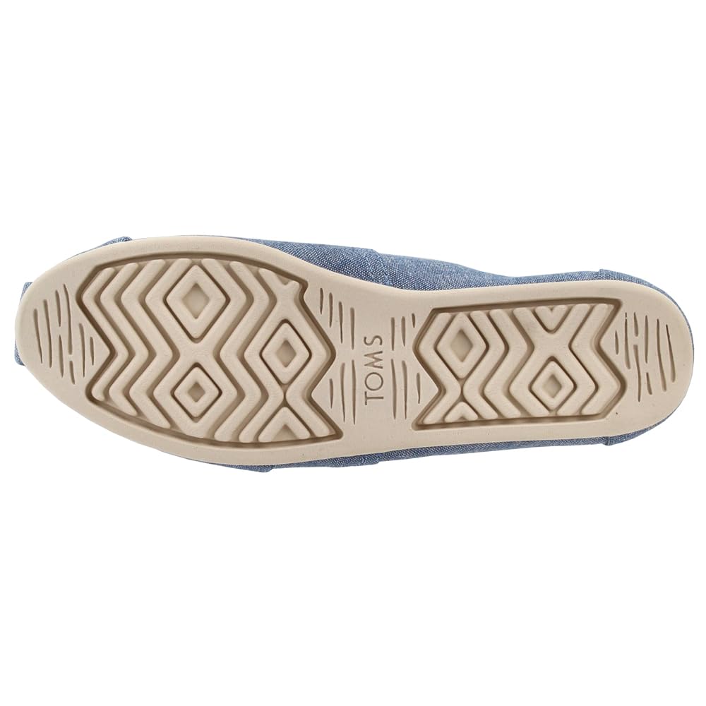 The image shows the beige rubber sole of the TOMS Alpargata ESP - Women slip-on, with geometric tread patterns and the TOMS brand name embossed in the center. The upper part of the shoe is blue.