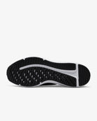 The image displays the black and white rubber outsole of the Nike Downshifter 12 - Women, viewed from below, showcasing its textured tread pattern made for grip, traction, and lightweight support.