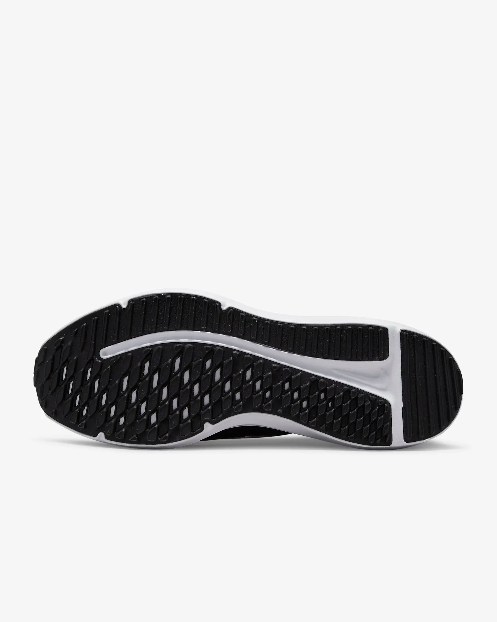 The image displays the black and white rubber outsole of the Nike Downshifter 12 - Women, viewed from below, showcasing its textured tread pattern made for grip, traction, and lightweight support.