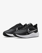 A pair of Nike Downshifter 12 - Women running shoes in Black/Smoke Grey/Pure Platinum/White, featuring white swooshes and soles, designed for lightweight support, shown angled on a plain white background.