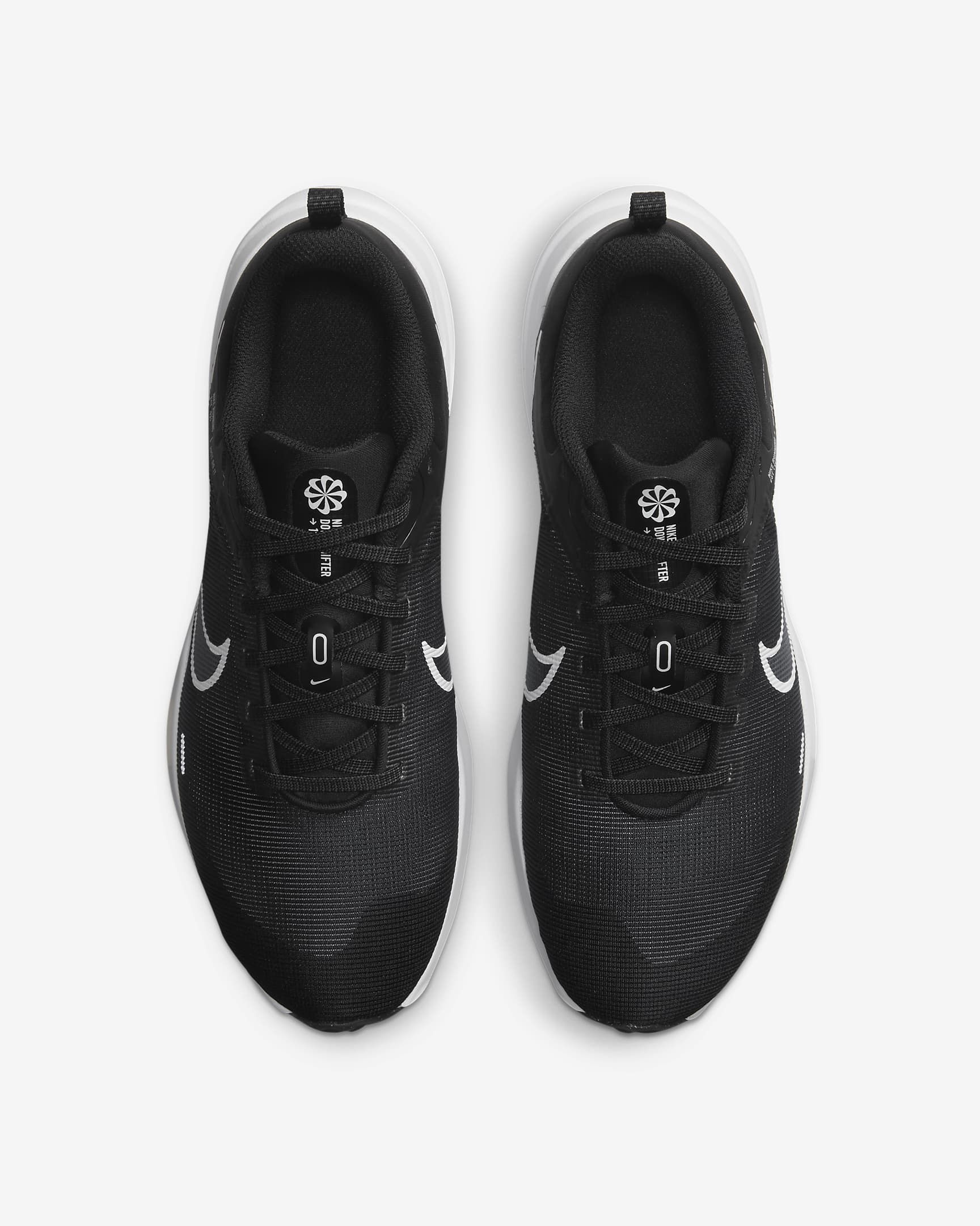A pair of Nike Downshifter 12 - Women black running shoes with white soles and swoosh logos, designed for lightweight support, shown from above on a white background.