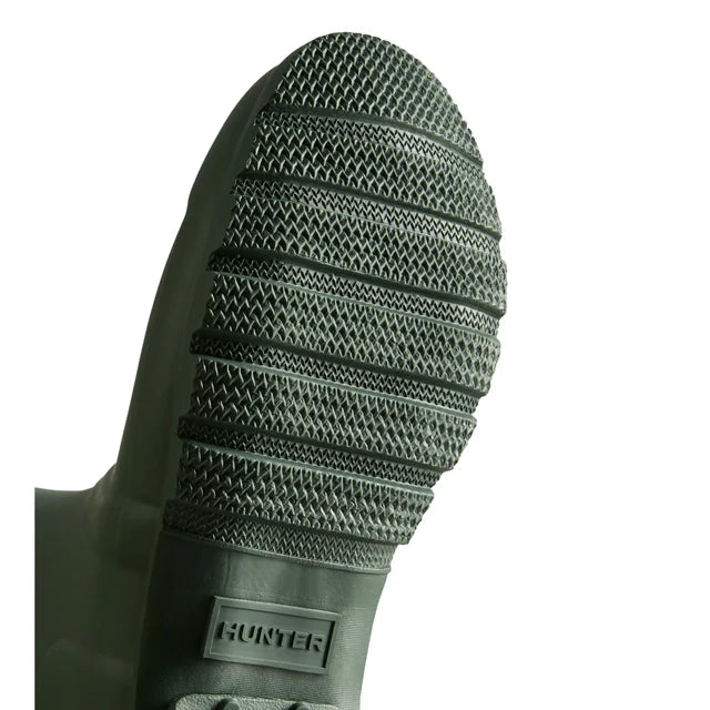 Close-up of the tread on the sole of Hunter Original Short Rain Boots for women, crafted from natural rubber with textured grip patterns. The Hunter brand name appears on a rectangular label near the heel.
