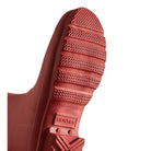 Close-up of the textured red sole on Hunters Original Short Rain Boots for women, featuring a patterned grip and embossed logo. Set against a plain white background, these standout festival boots are perfectly showcased.